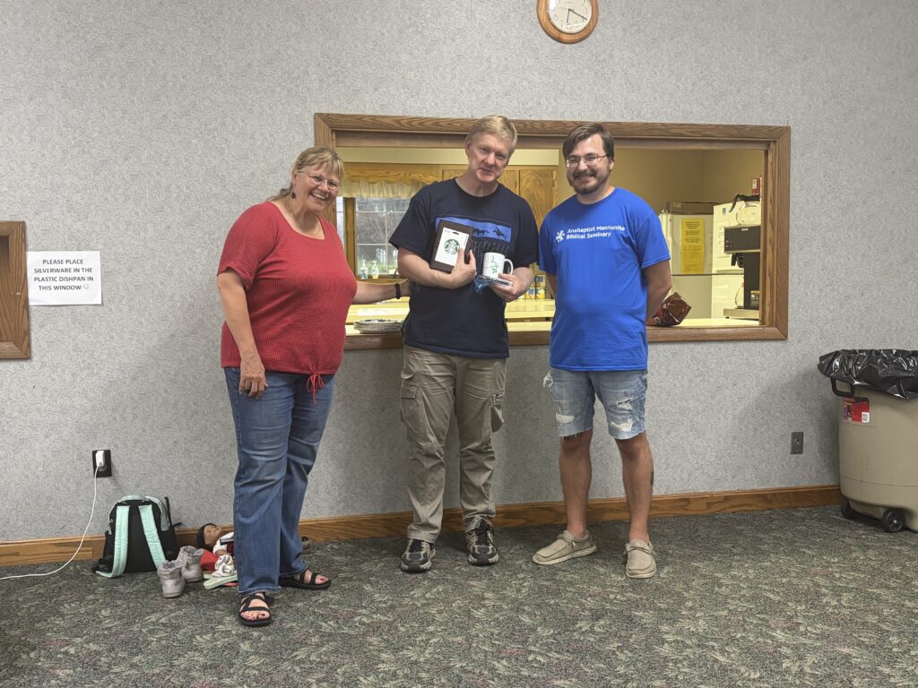 Three members of New Life Fellowship standing together by the kitchen counter, one holding a mug.